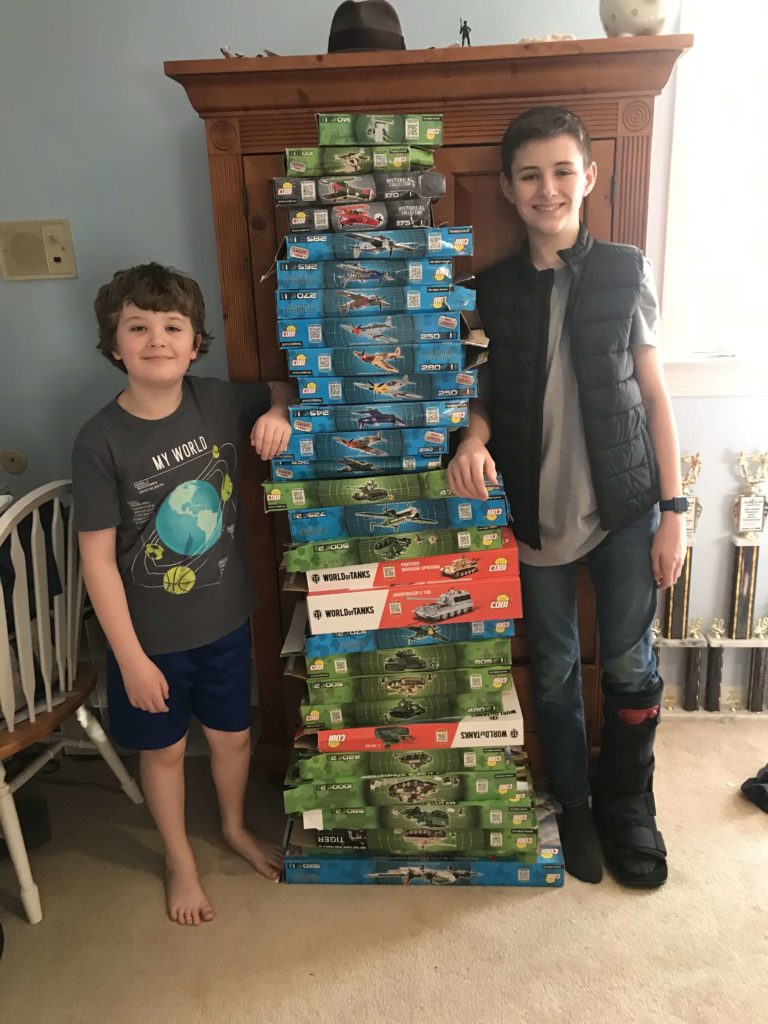 Two boys standing next to a stack of board games at Military Bricks.