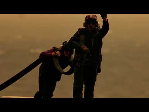 Top Gun opening scene showing U.S. Navy flight deck crew signaling aircraft operations at sunset aboard an aircraft carrier.